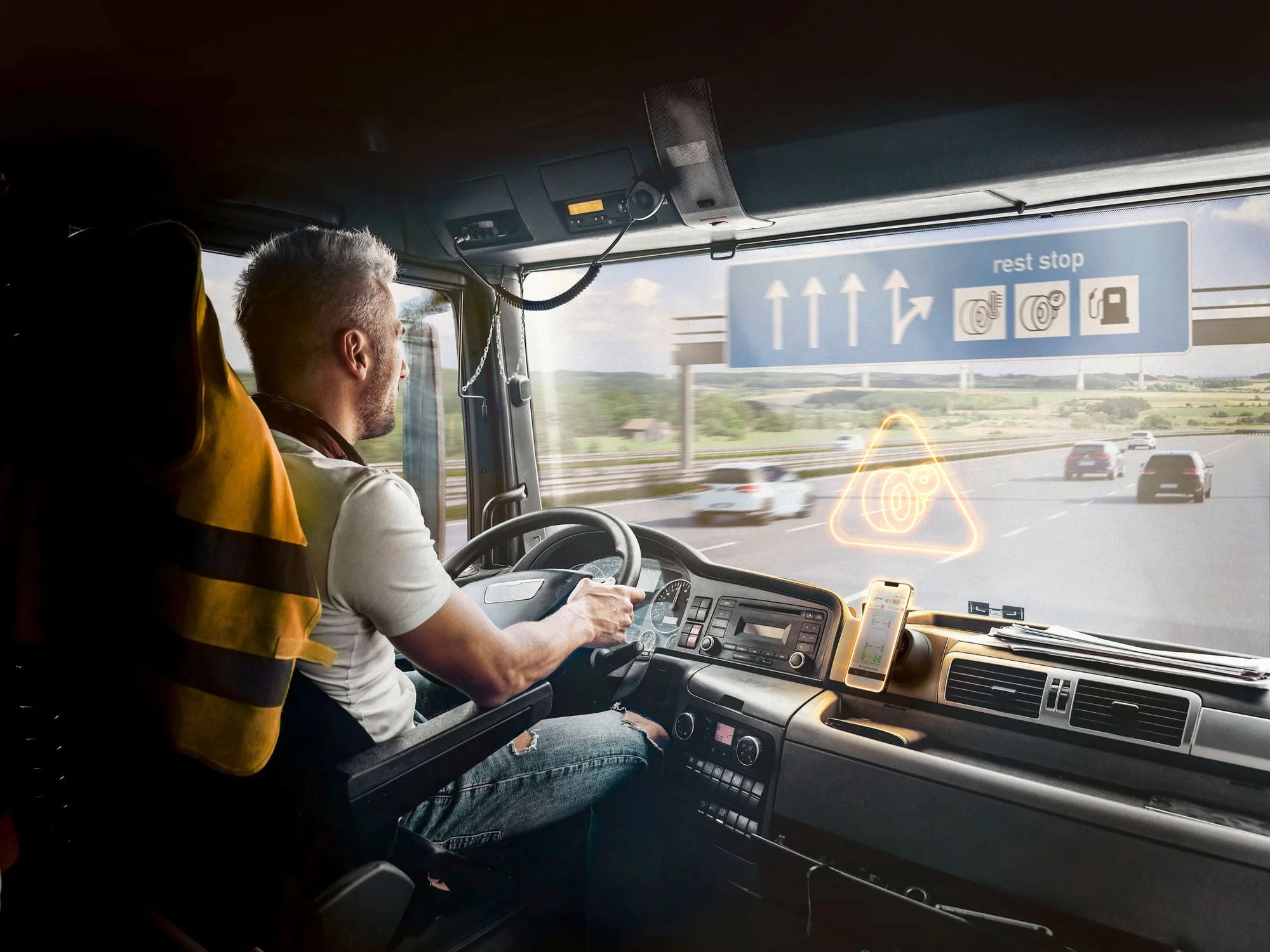 LKW-Fahrer von Hinten im LKW abgebildet, Handy mit der ContiConnect App daneben offen 