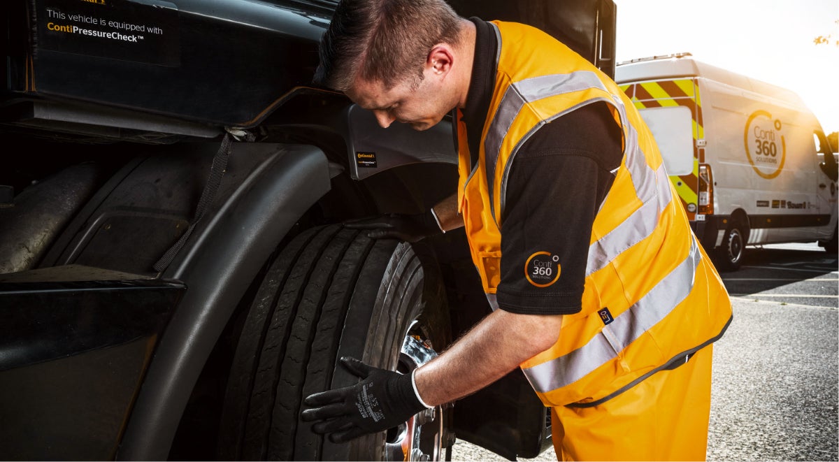 An employee examines a truck's tire