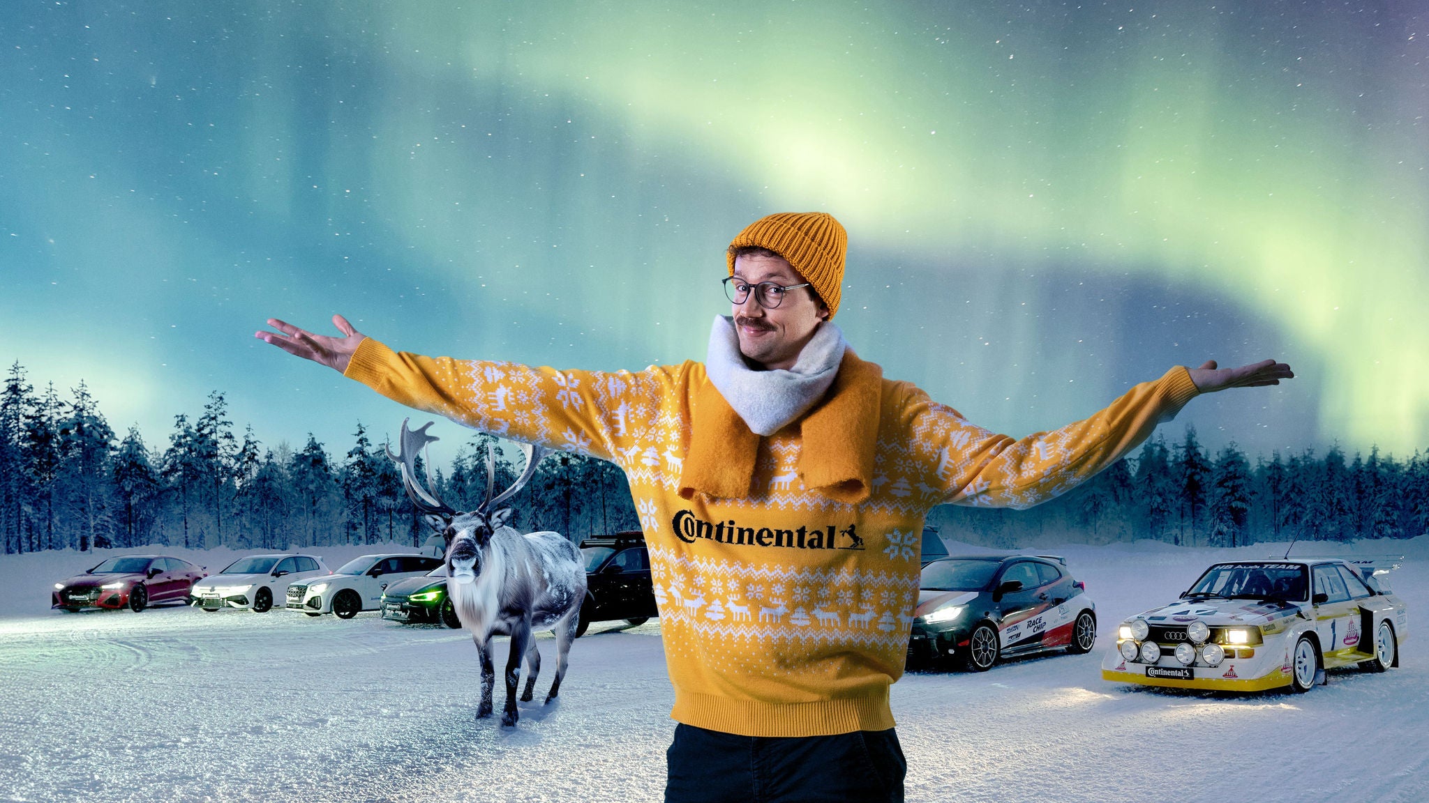 Mann in gelber Continental-Kleidung vor verschneiter Landschaft mit Polarlichtern, Autos und Rentier im Hintergrund.