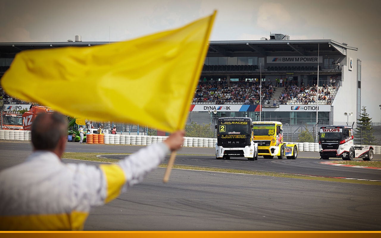 man next to a Grand Prix track waving a flag