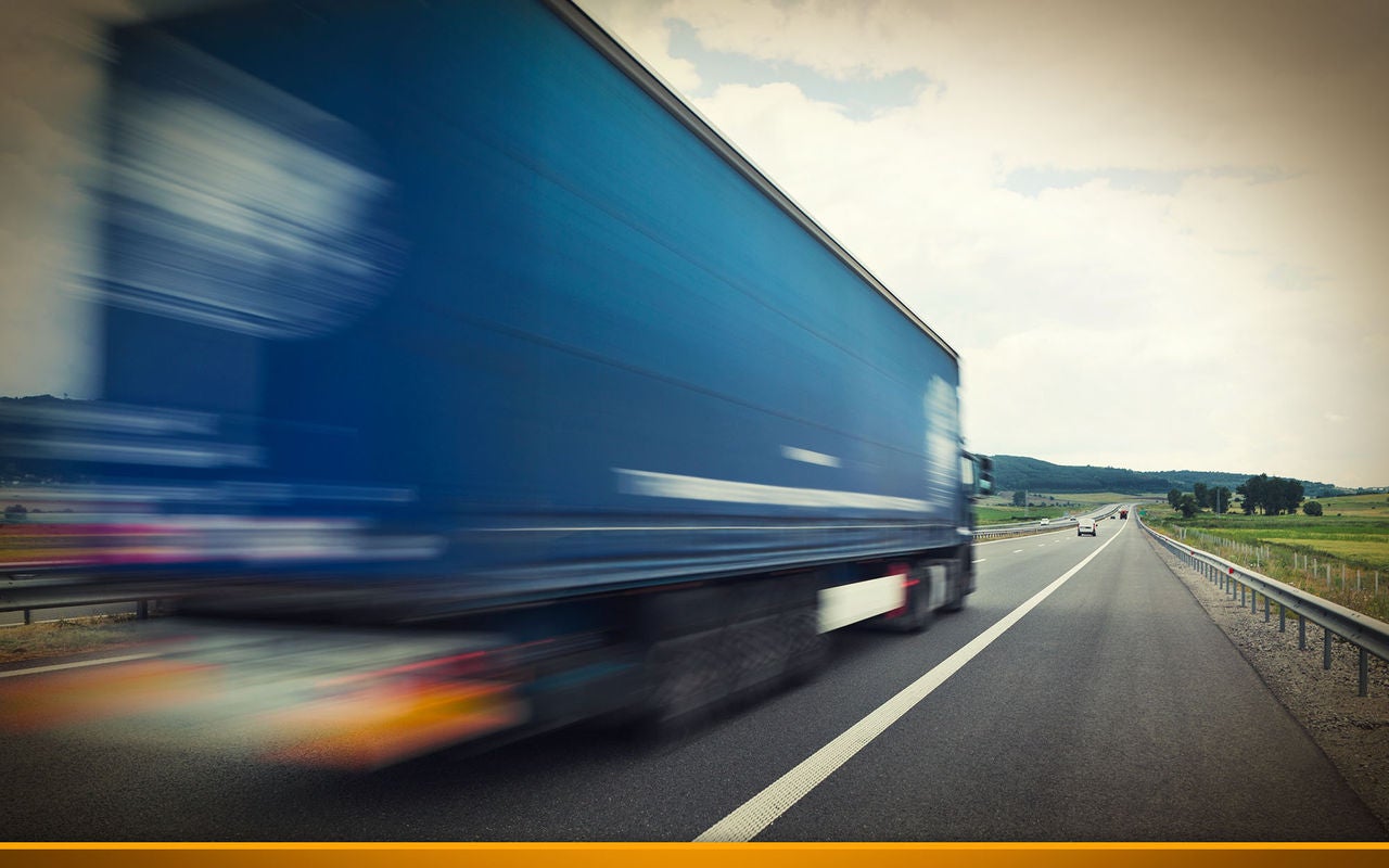 Blue truck driving fast on a highway