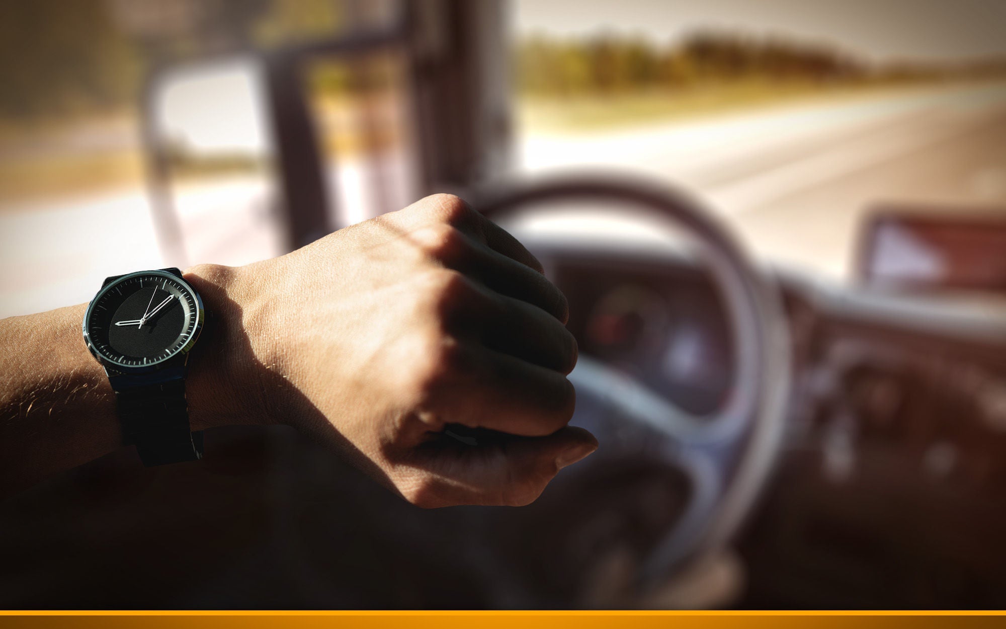 man on a steering wheel of a truck showing his clock