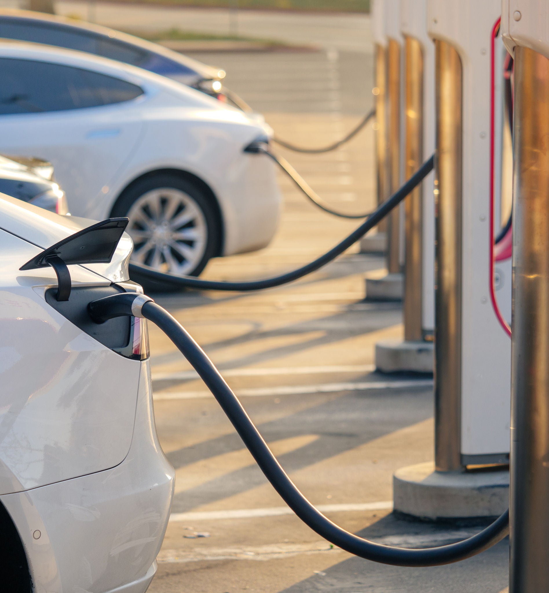 Electric cars charging at charging station outdoors at sunset. Tesla Electric Vehicle at Charging Station