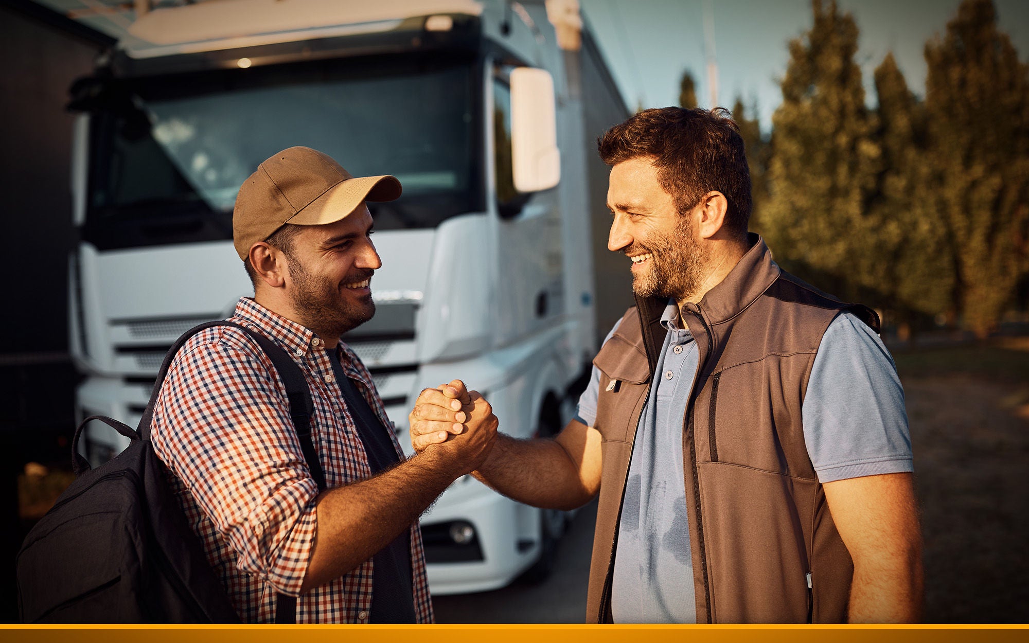 Happy professional drivers greet on truck parking lot.