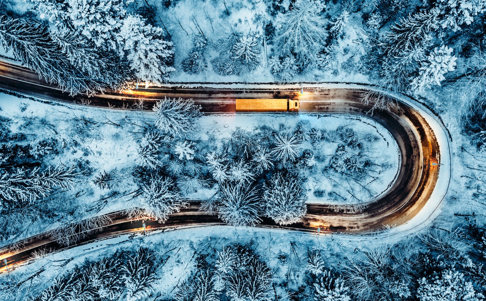 Weißes Auto auf einer kurvenreichen Straße im Winter