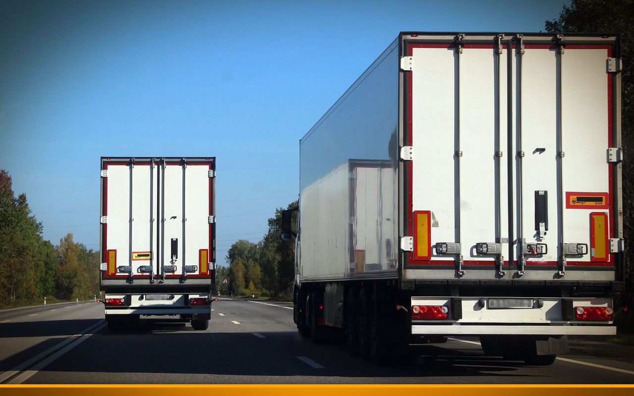 Two trucks on the road in summer against the blue sky