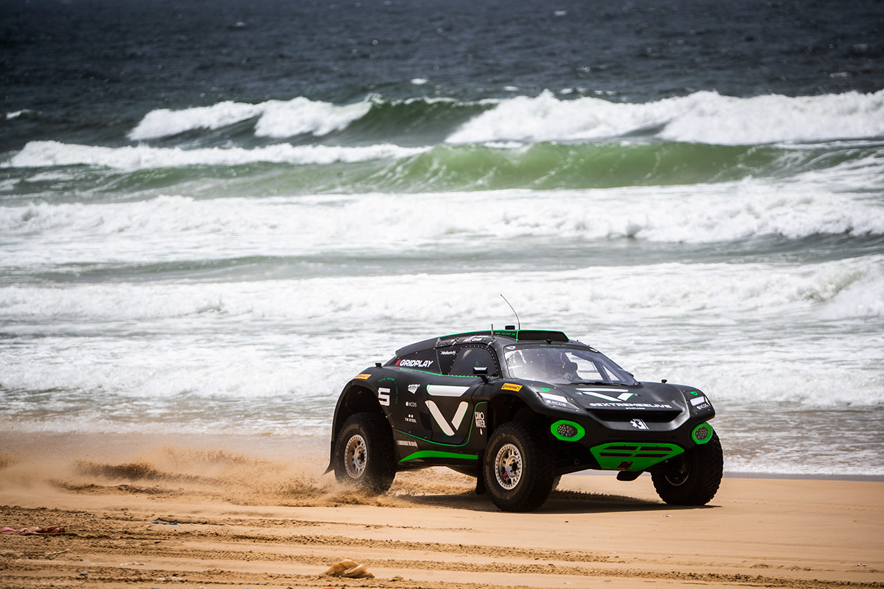 An Extreme E Race car driving along the beach in Senegal