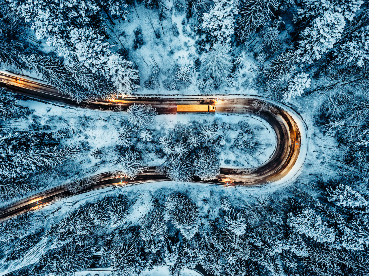 White car passing on an extreme winding road in wintertime