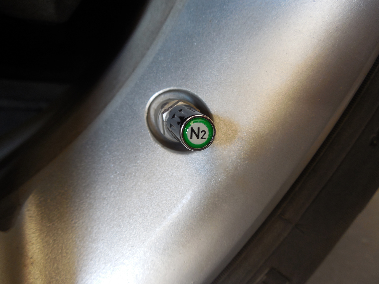 Chrome nitrogen (N2) TPMS-safe valve cap installed on an aluminum TPMS stem in an alloy wheel