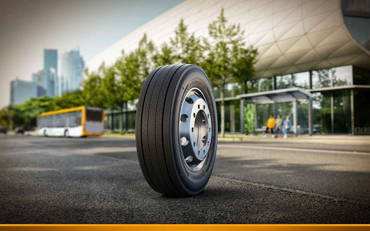 Close-up of the new city bus tire Conti Urban HA 5 NXT on a city street with a bus stop and modern buildings in the background