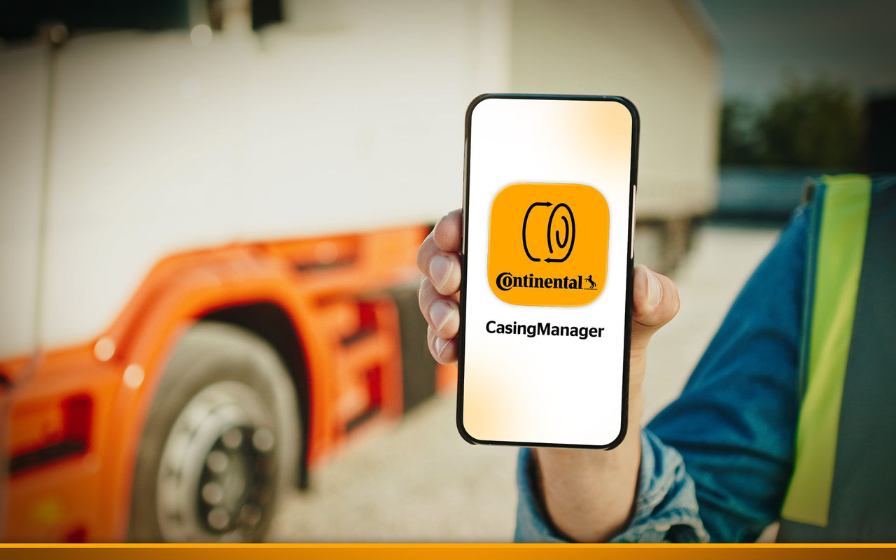 Truck driver holding smartphone with the "CasingManager" App from Continental