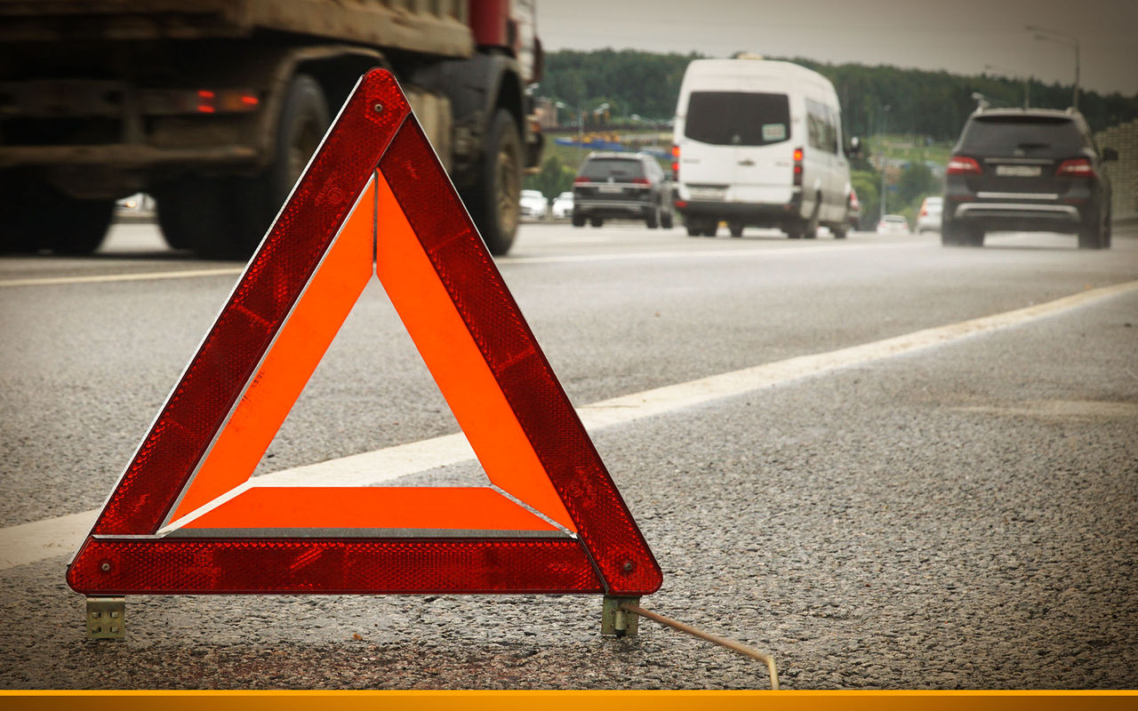 a warning road sign for an emergency stop stands on the asphalt against the background of moving cars