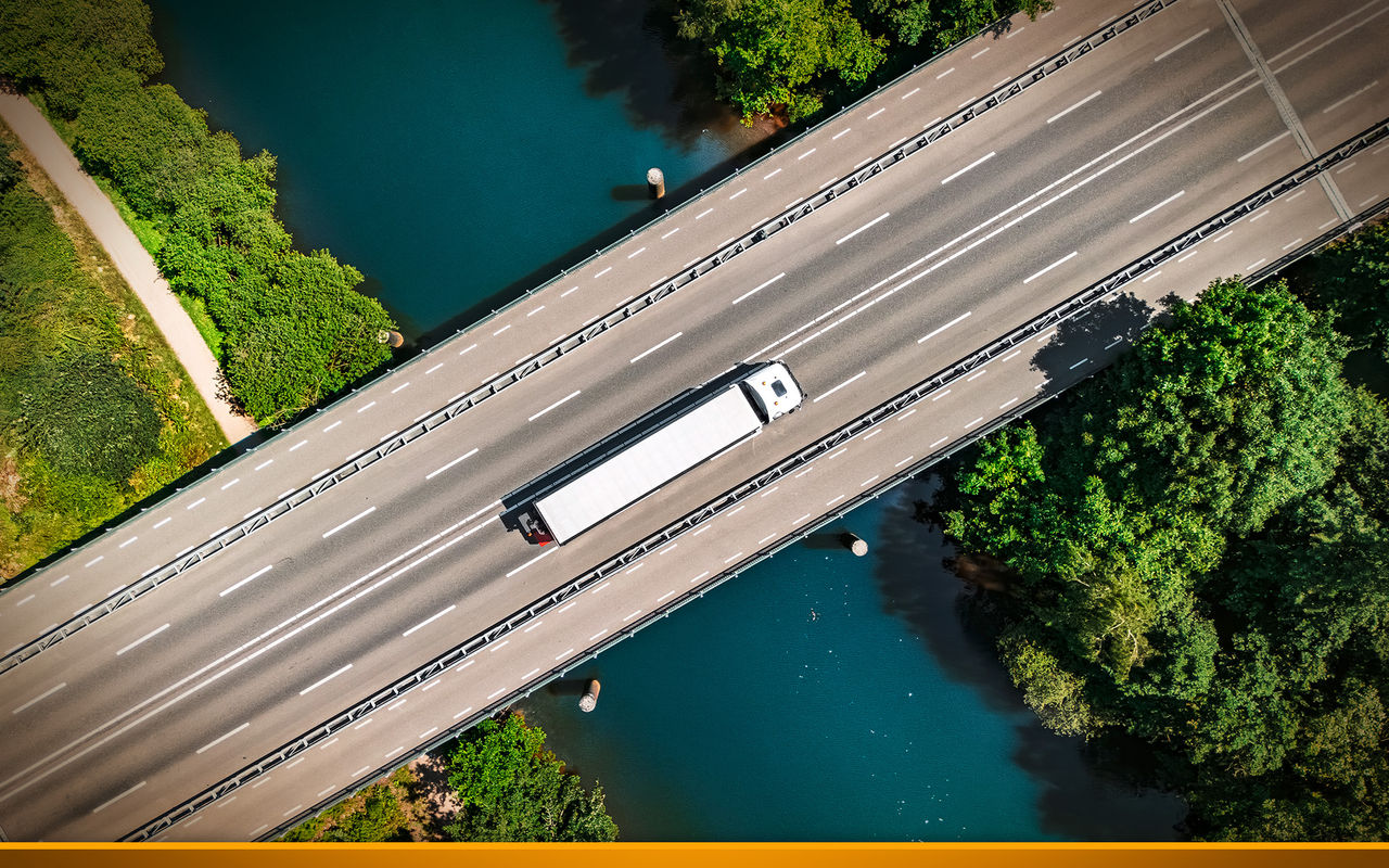 Overhead view of a lone truck traveling along a bridge.