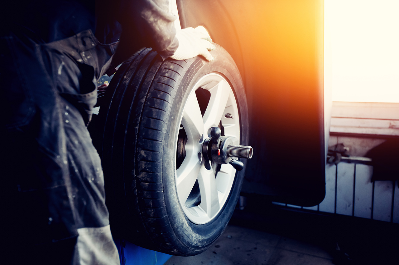 Repairman balances the wheel Ein Mechaniker wuchtet das Rad aus und montiert den schlauchlosen Reifen des Autos auf der Auswuchtmaschine in der Werkstatt.