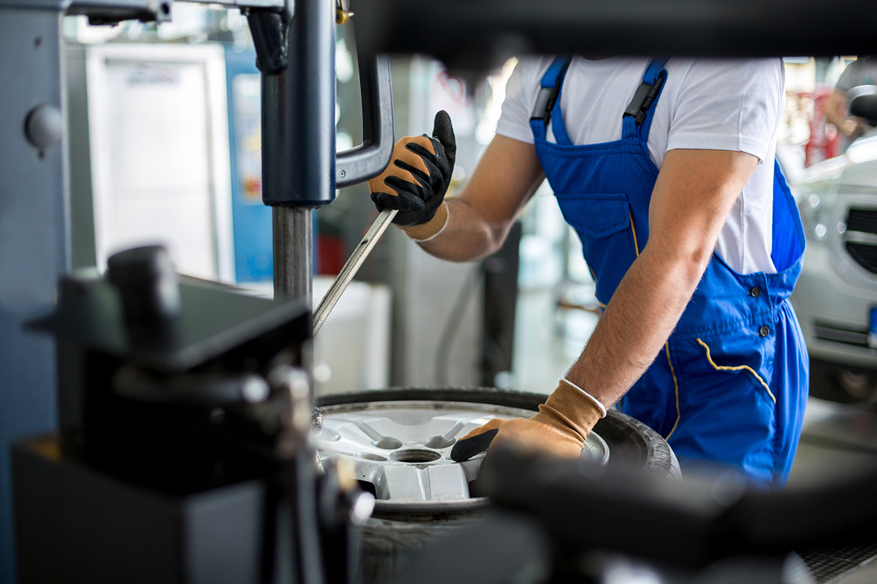 Mechaniker mit einem Reifen in der Werkstatt