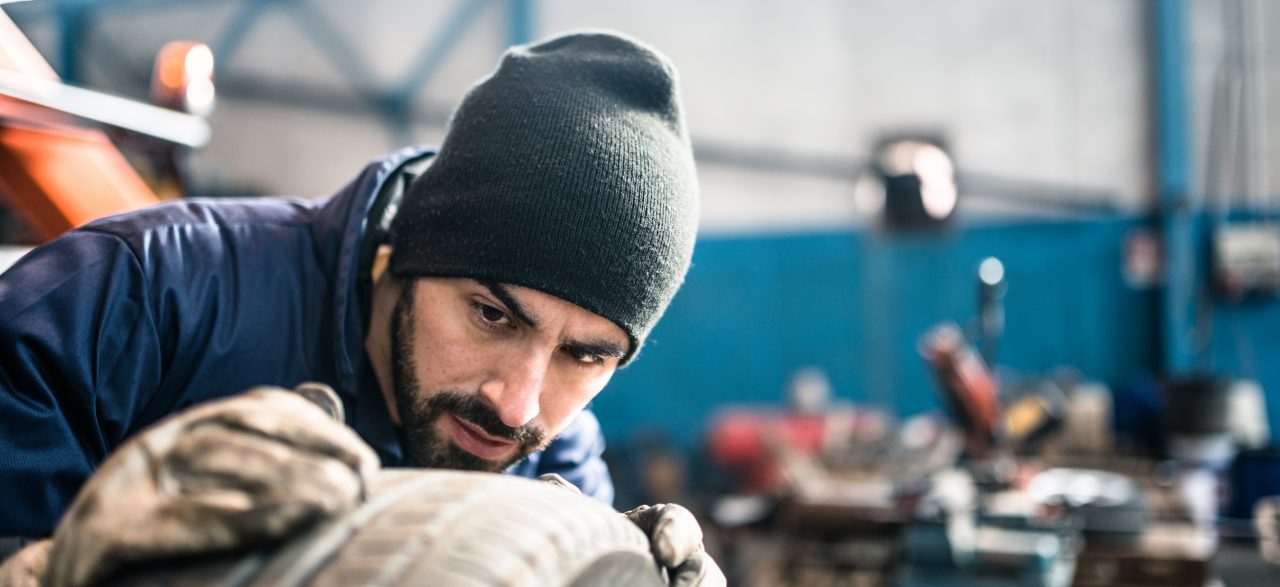 Mechaniker in einer Werkstatt untersucht das Reifenprofils